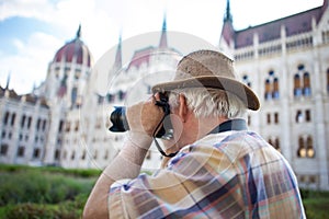 Senior pensioner photographing Parliament Building Budapest