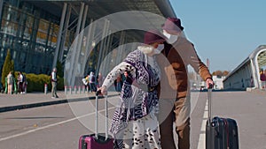 Senior pensioner tourists grandmother grandfather walking from airport with luggage, coronavirus