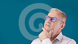 Senior pensive man portrait on blue background