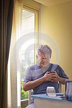 Senior people 50 heart disease showing pain, heart attack, weakness, fatigue and shortness of breath, sits with his hands over his