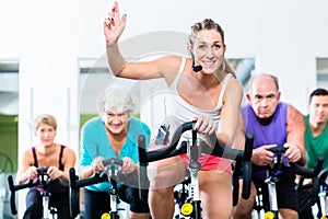 Senior people in gym spinning on fitness bike