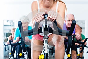 Senior people in gym spinning on fitness bike