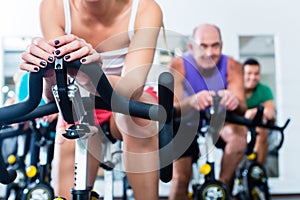 Senior people in gym spinning on fitness bike