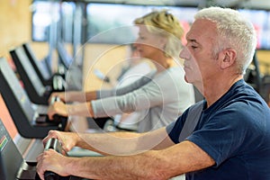 Senior people in gym spinning on fitness bike