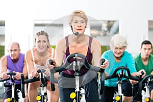 Senior people in gym spinning on fitness bike