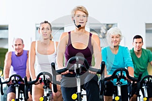 Senior people in gym spinning on fitness bike