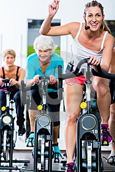 Senior people in gym spinning on fitness bike