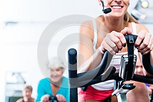 Senior people in gym spinning on fitness bike