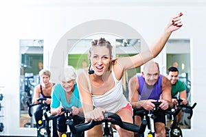 Senior people in gym spinning on fitness bike