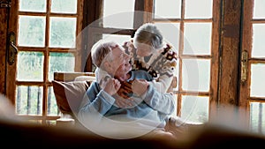 Senior people at home in love kissing and caring each other. Happy relationship mature man and woman together. Old male sitting on