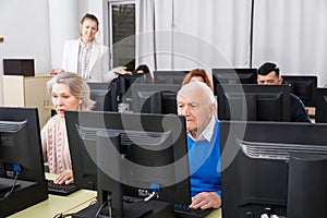Senior people learning to use computers with young tutor