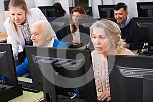 Senior people learning to use computers with young tutor