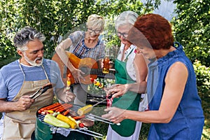 Senior people are making barbeque, drinking beverages, making memories, and laughing