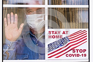 A senior people man behind the window of home stay at home wearing surgical mask to avoid contagion of coronavirus Covid-19 -