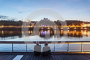 Senior people, and old couple of lovers, sitting on the quays of the riverbank of the rhone admiring the river during a summer