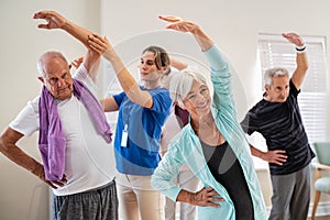 Senior people stretching with trainer at retirement community