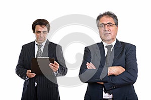 Senior Persian businessman with arms crossed and young Persian b