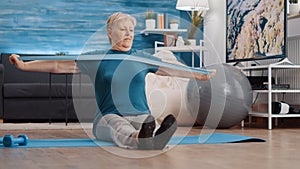 Senior person pulling resistance band to exercise on yoga mat