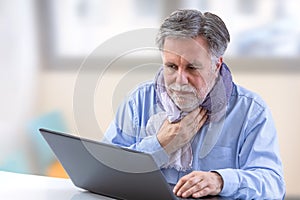 Senior person sitting with his latop at a table having a video call with her doctor, modern lifestyle concept