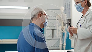 Senior physician doing ear examination with otoscope