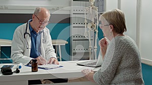 Senior physician taking examination notes on checkup files report