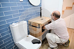 Senior plumber installer installing sink drain tube.