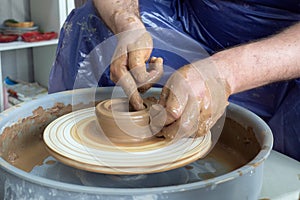 senior pottery man hands sculping from clay on pottery wheel pot in workshop