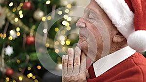 senior praying sitting by christmas tree at home