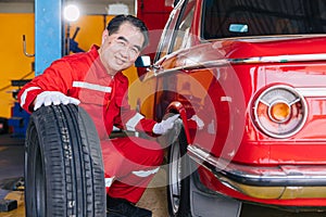 Senior professional Asian male mechanic garage worker happy working tyre wheels replacing car tire maintenance service