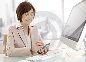 Senior professional woman using pda in office