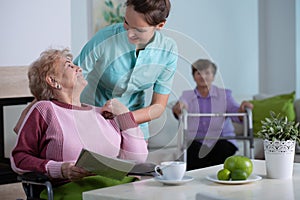 Senior residents in living room of nursing facility with supporting nurse