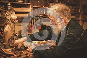 Senior restorer working with antique decor element in his workshop