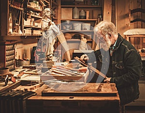 Senior restorer working with antique decor element in his workshop