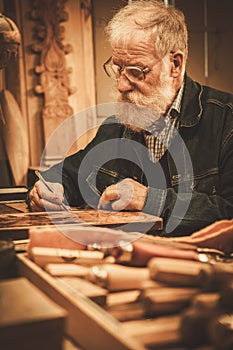 Senior restorer working with antique decor element in his workshop