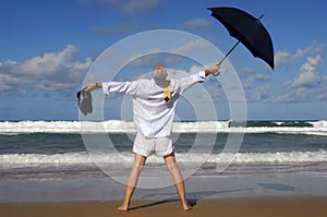 Senior retired business man, arms outstretched celebrating freedom on a tropical beach