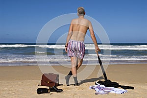 Senior retired business man undressing on caribbean beach, retirement freedom escape concept