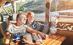 Senior retired couple of happy vacationers taking selfie at Mekong exploration tour with slowboat in Laos PDR - Active elderly