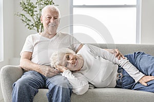 senior retired couple having great moment together on cozy sofa in living room.