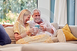Senior Retired Couple Relaxing On Sofa At Home With Hot Drink