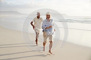 Senior Retired Couple Running Along Summer Beach Together