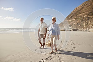 Senior Retired Couple Walking Along Beach Hand In Hand Together