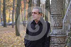 Senior retired man on beautiful autumn day in park stands and rests