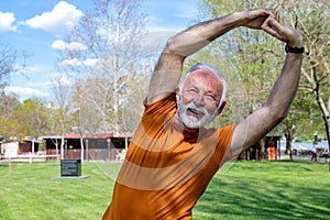 A senior retired man stretching in the park.