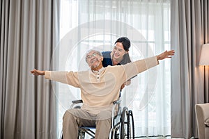 senior retired old man sitting on wheelchair having fun with young woman nurse