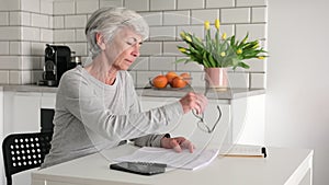 Senior Retired Woman Checking Data In Contract In The Kitchen At Home