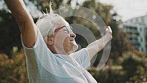 Senior retired woman enjoying freedom of retirement. Outstretched hands in the park, close up