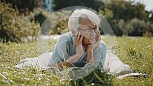 Senior retired woman enjoying the sunny autumn day in the park