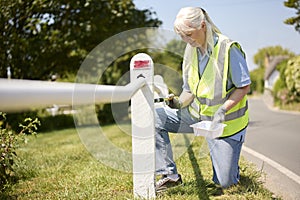 Senior Retired Woman Helping To Maintain Community By Painting Fence Post