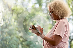 Senior Retired Woman Outside In Garden At Home Using Digital Tablet