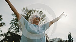 Senior retired woman in the park with outstretched hands low angle shot